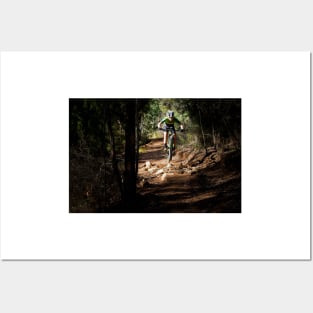 Mountain Biker getting air on a dark single track Posters and Art